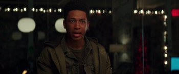 Movie still from “Collateral Beauty” (2016), directed by David Frankel – A young man in a green jacket looking at the camera; Close Up shot, Over the shoulder angle