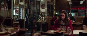 Movie still from “Collateral Beauty” (2016), directed by David Frankel – A woman sitting at a table in front of a christmas tree; Medium shot, Over the shoulder angle