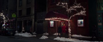 Movie still from “Collateral Beauty” (2016), directed by David Frankel – People are standing outside of a restaurant on a snowy night; Extreme Wide shot, Low angle