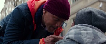 Movie still from “Collateral Beauty” (2016), directed by David Frankel – A man wearing a purple hat touching a person's face; Close Up shot, Over the shoulder angle
