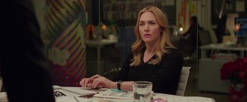 Movie still from “Collateral Beauty” (2016), directed by David Frankel – A woman sitting at a table with papers in front of her; Medium shot, Over the shoulder angle