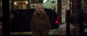 Movie still from “Collateral Beauty” (2016), directed by David Frankel – An older woman standing on the sidewalk at night; Medium shot, Over the shoulder angle