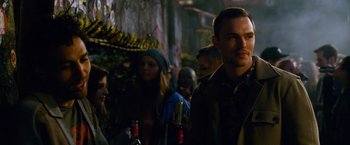 Movie still from “Collide” (2016), directed by Eran Creevy – A group of people standing next to each other on a street; Close Up shot, Over the shoulder angle