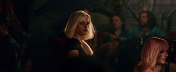Movie still from “Collide” (2016), directed by Eran Creevy – A woman with blonde hair is standing in a dark room; Close Up shot, Over the shoulder angle