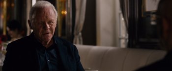 Movie still from “Collide” (2016), directed by Eran Creevy – An older man sitting on a couch in front of a window; Close Up shot, Over the shoulder angle