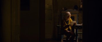 Movie still from “Collide” (2016), directed by Eran Creevy – A woman sitting on a chair looking at a tablet computer; Wide shot, High angle