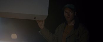 Movie still from “Collide” (2016), directed by Eran Creevy – A man holding a pizza box in a dark room; Medium shot, Low angle