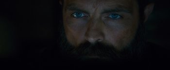 Movie still from “Collide” (2016), directed by Eran Creevy – A man with a beard and blue eyes; Extreme Close Up shot, Low angle