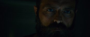 Movie still from “Collide” (2016), directed by Eran Creevy – A person with a beard looking at the camera; Extreme Close Up shot, Low angle
