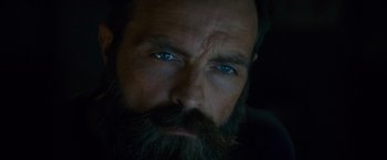 Movie still from “Collide” (2016), directed by Eran Creevy – A man with a long beard and blue eyes; Extreme Close Up shot, Low angle