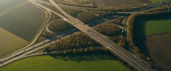 Movie still from “Collide” (2016), directed by Eran Creevy – An aerial view of a highway with a lot of trees; Extreme Wide shot, High angle