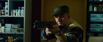 Movie still from “Collide” (2016), directed by Eran Creevy – A man holding a gun in his hand; Medium shot, Low angle