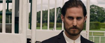 Movie still from “Collide” (2016), directed by Eran Creevy – A person wearing a suit and tie; Close Up shot, Over the shoulder angle