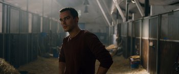 Movie still from “Collide” (2016), directed by Eran Creevy – A man standing in a barn with his hands on his hips; Medium shot, Over the shoulder angle