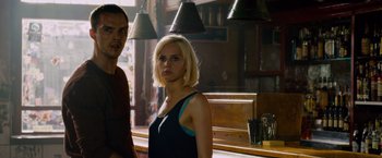 Movie still from “Collide” (2016), directed by Eran Creevy – A man and a woman standing in front of a bar; Medium shot, Low angle