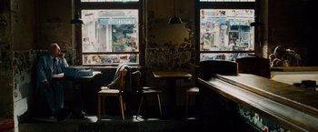 Movie still from “Collide” (2016), directed by Eran Creevy – Two chairs and a table in front of a window in a restaurant; Wide shot, Over the shoulder angle