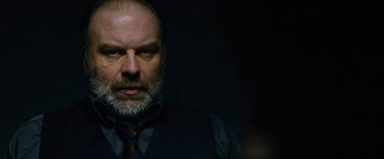 Movie still from “Collide” (2016), directed by Eran Creevy – A person wearing a suit and tie; Close Up shot, Over the shoulder angle