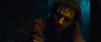 Movie still from “Collide” (2016), directed by Eran Creevy – A man with curly hair and a plaid shirt; Close Up shot, Low angle