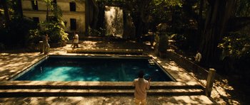 Movie still from “Colombiana” (2011), directed by Olivier Megaton – A man standing in front of a pool near a waterfall; Extreme Wide shot, High angle