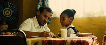 Movie still from “Colombiana” (2011), directed by Olivier Megaton – A man and a young girl sitting at a table; Medium shot, Over the shoulder angle
