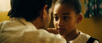 Movie still from “Colombiana” (2011), directed by Olivier Megaton – A young girl looking at the camera with a man touching her shoulder; Close Up shot, Over the shoulder angle