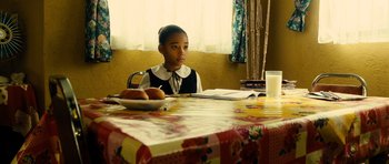 Movie still from “Colombiana” (2011), directed by Olivier Megaton – A girl sitting at a table in front of a bowl of apples; Medium shot, Over the shoulder angle