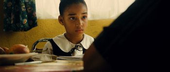 A young girl sitting at a table looking at a book