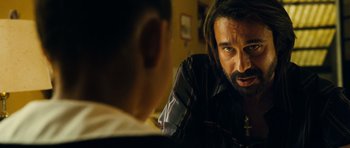 Movie still from “Colombiana” (2011), directed by Olivier Megaton – A man with long hair and beard talking to another man; Close Up shot, Over the shoulder angle