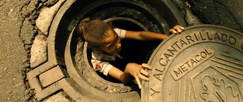 Movie still from “Colombiana” (2011), directed by Olivier Megaton – A young girl climbing into an old car tire; Medium shot, Overhead angle