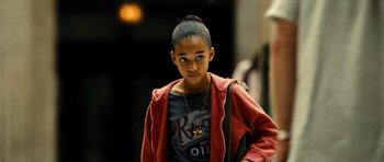 Movie still from “Colombiana” (2011), directed by Olivier Megaton – A young boy with a necklace is posing for a picture; Close Up shot, High angle