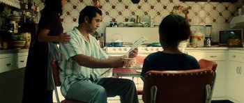 Movie still from “Colombiana” (2011), directed by Olivier Megaton – A man sitting at a table with a bowl of food; Medium shot, Over the shoulder angle