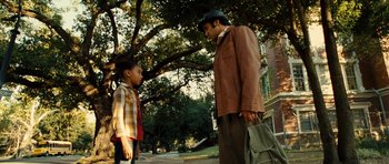 Movie still from “Colombiana” (2011), directed by Olivier Megaton – A man and a boy standing next to each other on the sidewalk; Medium shot, Over the shoulder angle