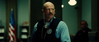 Movie still from “Colombiana” (2011), directed by Olivier Megaton – A man with a mustache wearing a vest; Close Up shot, Low angle