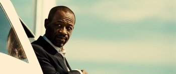 Movie still from “Colombiana” (2011), directed by Olivier Megaton – A man in a suit and tie with his arms crossed; Close Up shot, Low angle