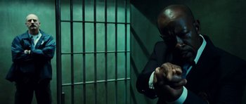 Movie still from “Colombiana” (2011), directed by Olivier Megaton – A man in a suit holding a cell phone; Medium shot, Low angle