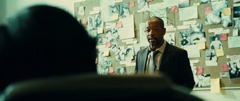 Movie still from “Colombiana” (2011), directed by Olivier Megaton – A man standing in front of a wall covered with papers; Close Up shot, Over the shoulder angle