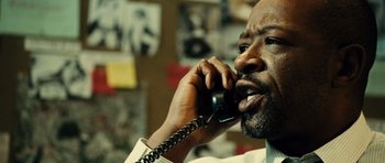 Movie still from “Colombiana” (2011), directed by Olivier Megaton – A man talking on a phone while sitting in a room; Close Up shot, Over the shoulder angle