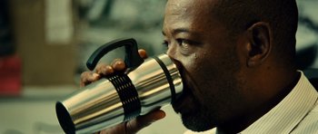 Movie still from “Colombiana” (2011), directed by Olivier Megaton – A person drinking out of a thermos; Extreme Close Up shot, Over the shoulder angle