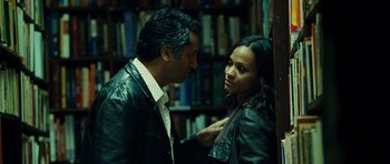 Movie still from “Colombiana” (2011), directed by Olivier Megaton – A man and a woman are standing in front of a bookshelf; Medium shot, Over the shoulder angle
