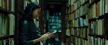 Movie still from “Colombiana” (2011), directed by Olivier Megaton – A woman is looking at a book in a library; Medium shot, Low angle