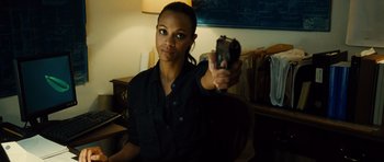 Movie still from “Colombiana” (2011), directed by Olivier Megaton – A woman holding a gun in a room; Close Up shot, Over the shoulder angle