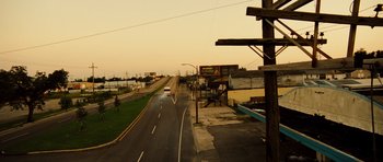 Movie still from “Colombiana” (2011), directed by Olivier Megaton – An empty street with a car driving down the road; Extreme Wide shot, High angle