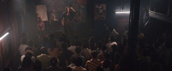 Movie still from “Colonia” (2015), directed by Florian Gallenberger – A crowd of people sitting in a dark room; Wide shot, High angle