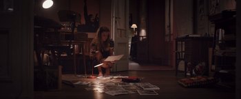 Movie still from “Colonia” (2015), directed by Florian Gallenberger – A woman sitting on the floor looking at papers on the floor; Wide shot, High angle