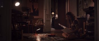 Movie still from “Colonia” (2015), directed by Florian Gallenberger – A woman sitting on the floor reading a book; Wide shot, High angle