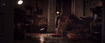 Movie still from “Colonia” (2015), directed by Florian Gallenberger – Two people sitting on the floor in a living room; Wide shot, High angle