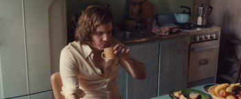 Movie still from “Colonia” (2015), directed by Florian Gallenberger – A man drinking a cup of coffee in a kitchen; Medium shot, Over the shoulder angle