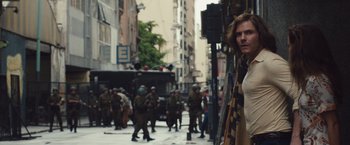 Movie still from “Colonia” (2015), directed by Florian Gallenberger – A group of people walking down a street; Medium shot, Over the shoulder angle