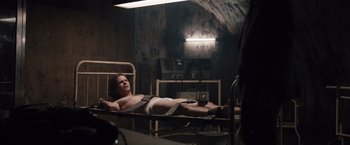 Movie still from “Colonia” (2015), directed by Florian Gallenberger – A man laying on a hospital bed in a room; Medium shot, High angle