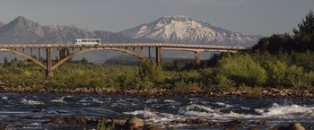 Movie still from “Colonia” (2015), directed by Florian Gallenberger – A bus driving on a bridge over a river; Extreme Wide shot, Low angle